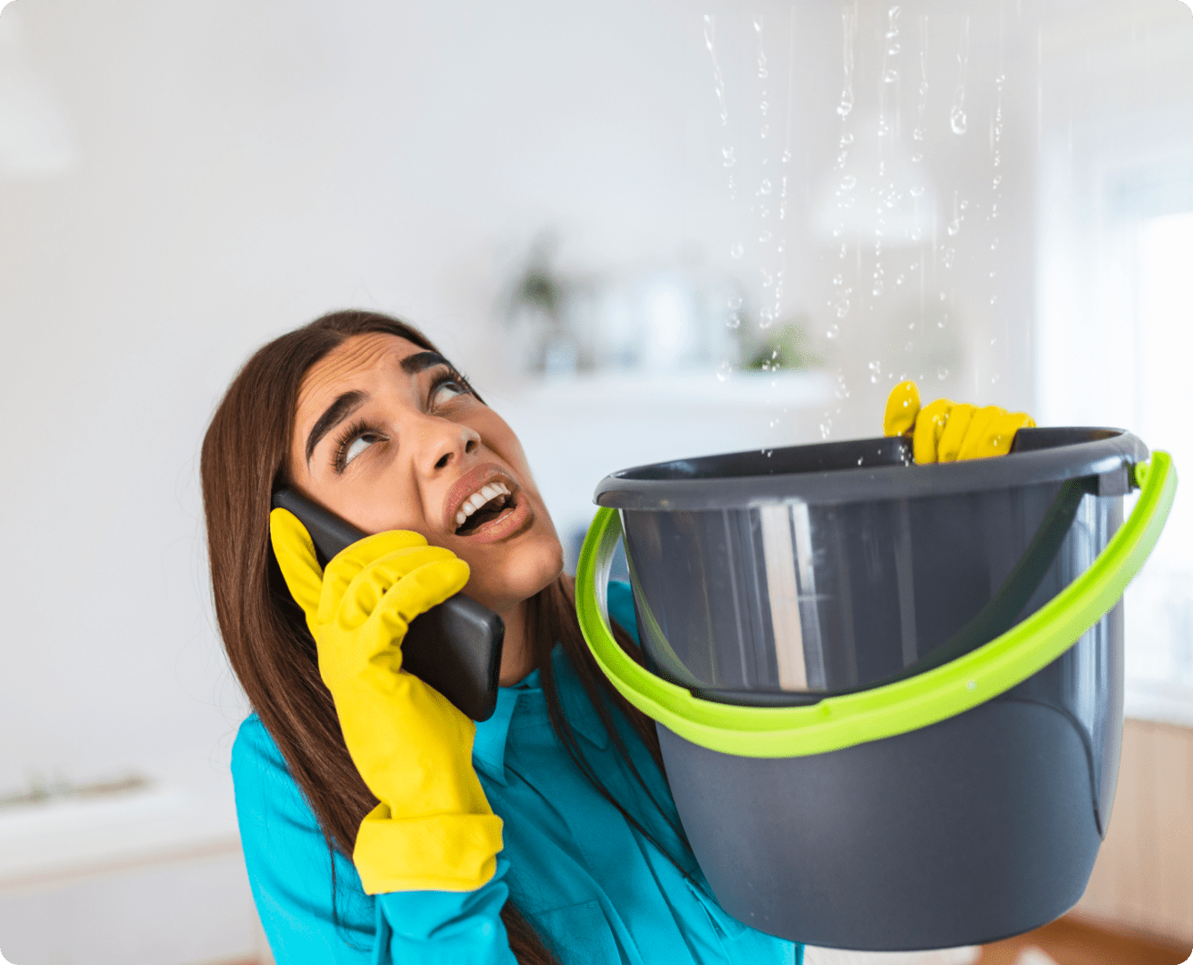 Woman catching leak with bucket, calling for help.