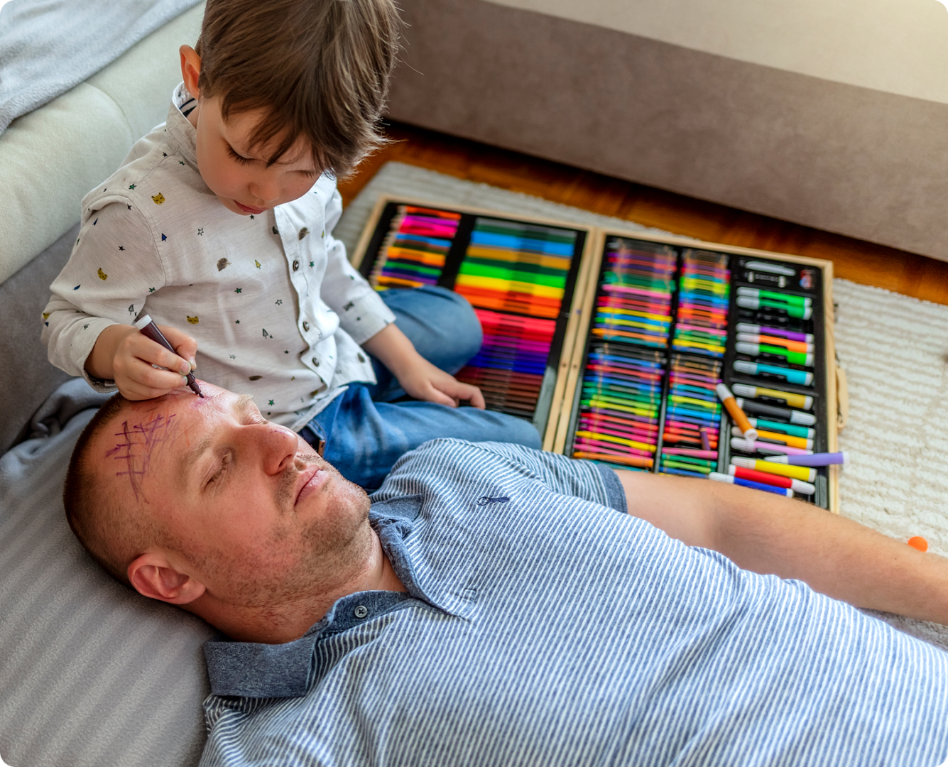 Child drawing on sleeping man's face.