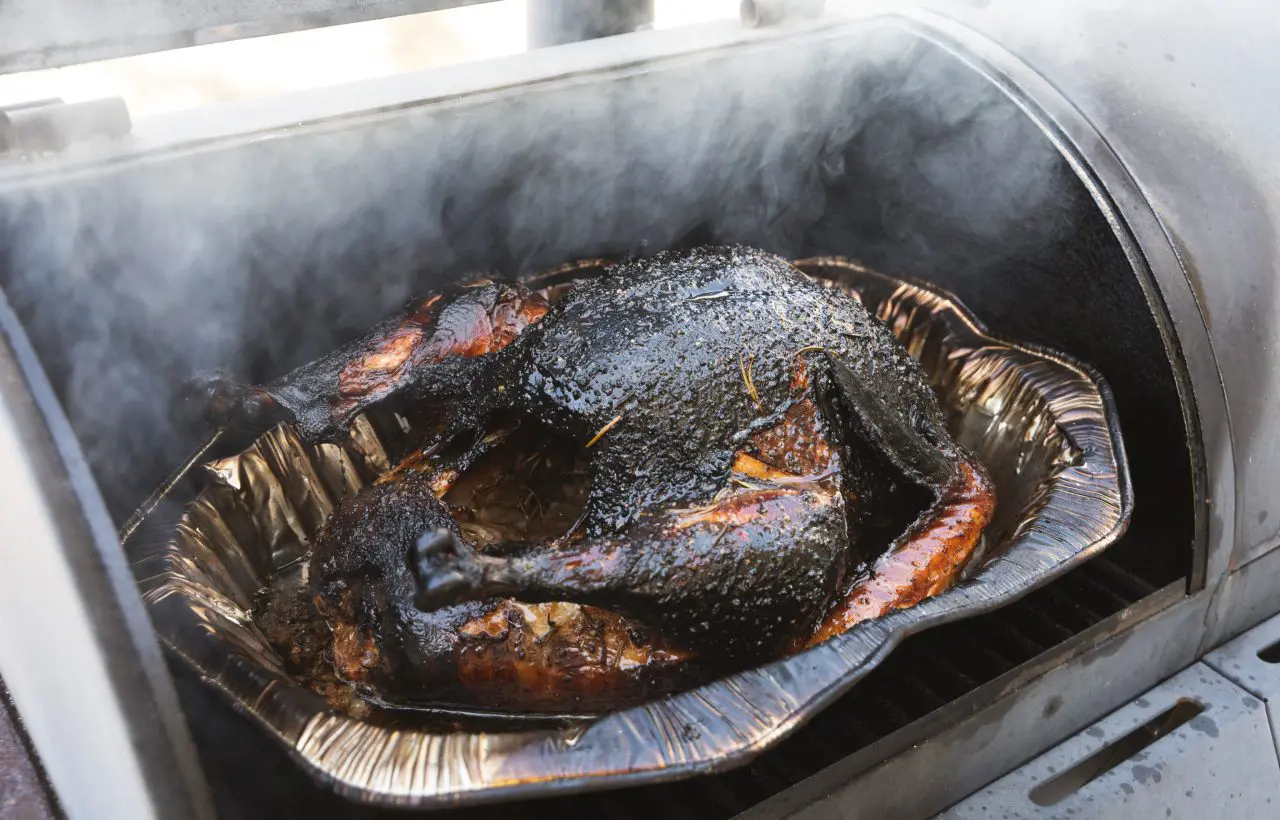 Smoked turkey in a grill with smoke.